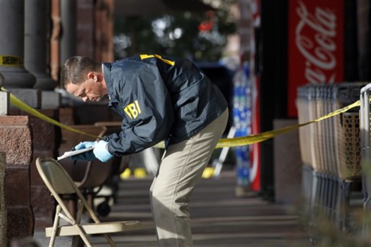 An FBI agent on Jan. 10 writes down information as he looks around the area at a local Safeway in Tucson, Ariz., where Rep. Gabrielle Giffords, D-Ariz., was shot, two days after a mass shooting there left six dead. 